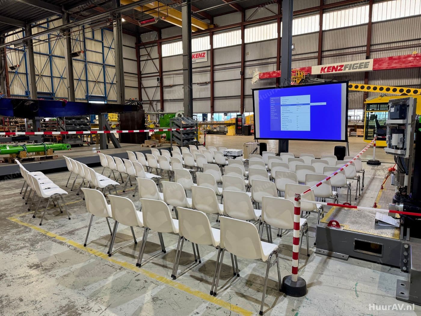 Congreszaal met publiek, sprekerspodium en groot projectiescherm