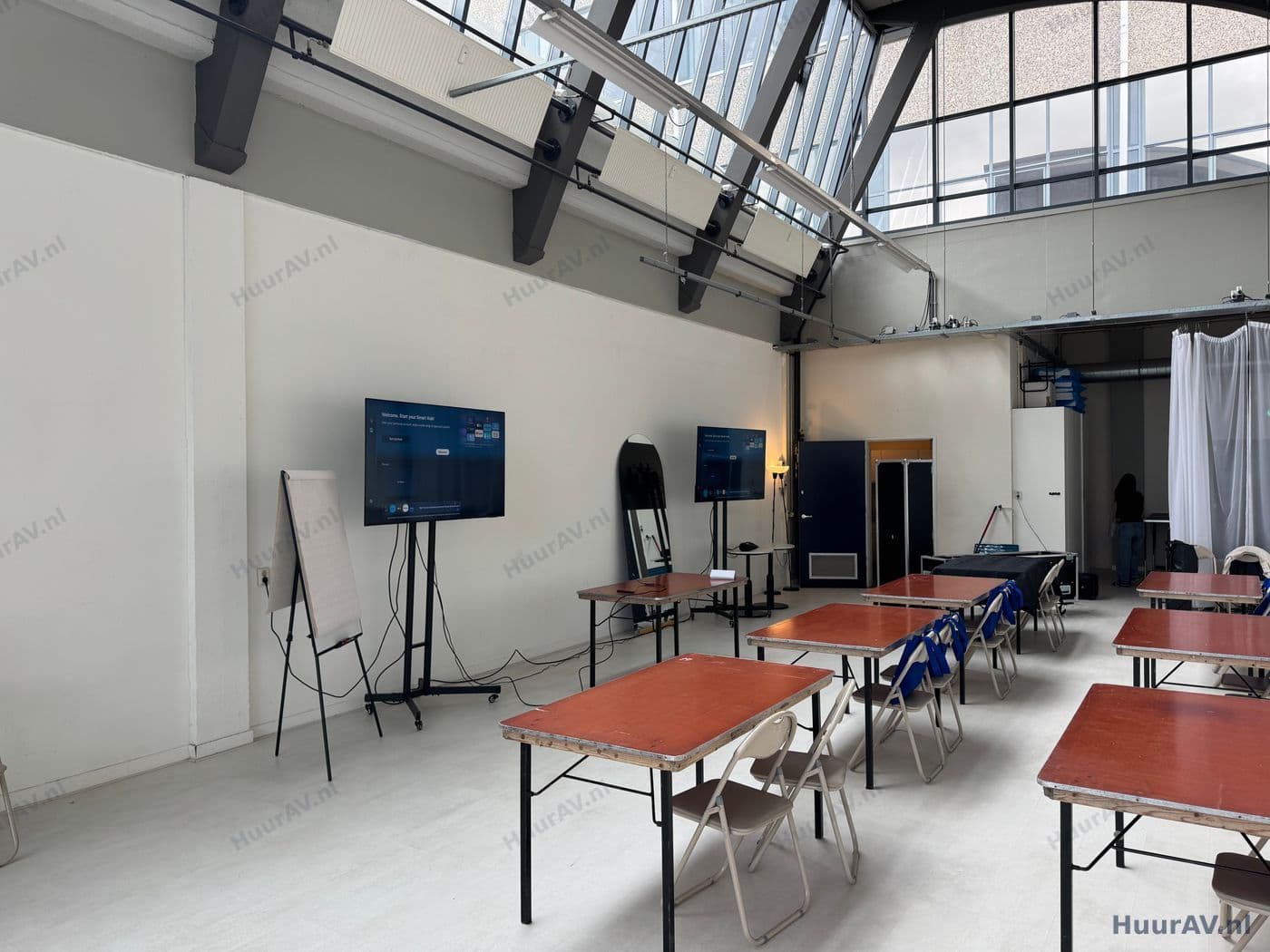 Trainer voor een groep deelnemers bij een seminar met een scherm en compacte geluidsopstelling